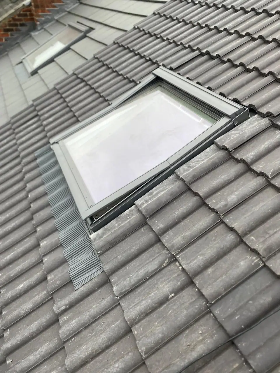 Flashing detail around a roof window in charcoal tiles